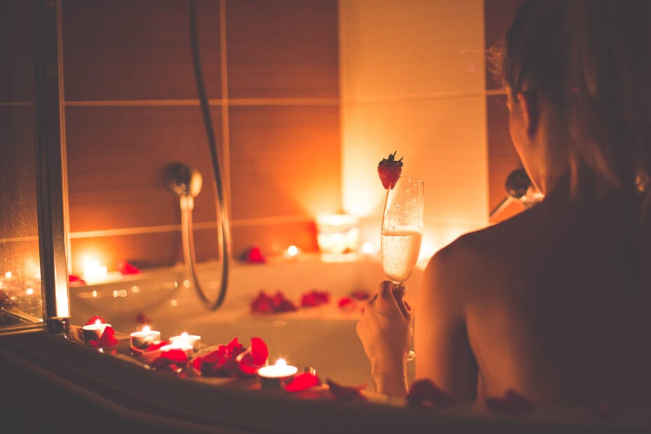 Coverbild zum Artikel über neue Begleitservices mit einer Frau in der Badewanne liegend mit Sektglas in der Hand bei Kerzenschein.